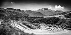 The terraces dip like a crater beneath a jagged road, while an off-center peak holds the frame in quiet tension. The land see