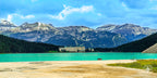 The Fairmont Château Lake Louise resort sits at the edge of a turquoise glacial lake, with towering mountain peaks in the ba