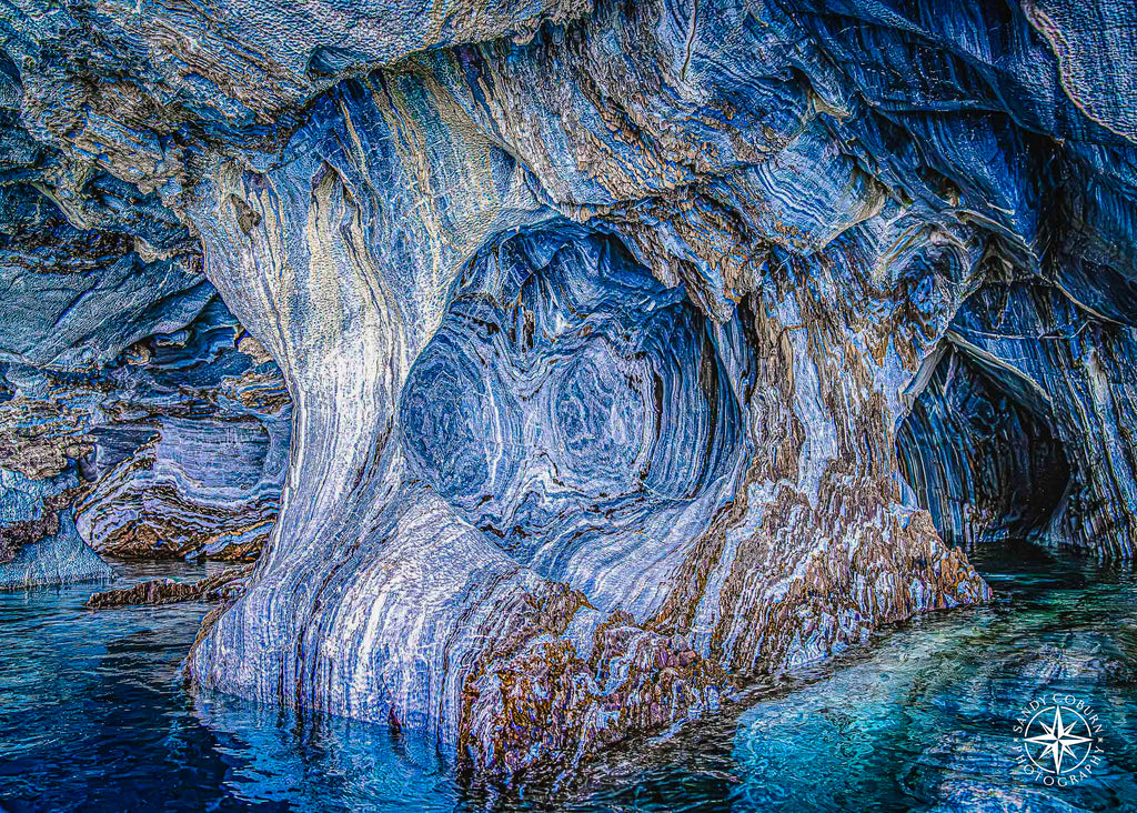 Blue-and-white marble spiral patterns framed by a cave arch above turquoise water.