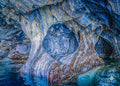 Blue-and-white marble spiral patterns framed by a cave arch above turquoise water.