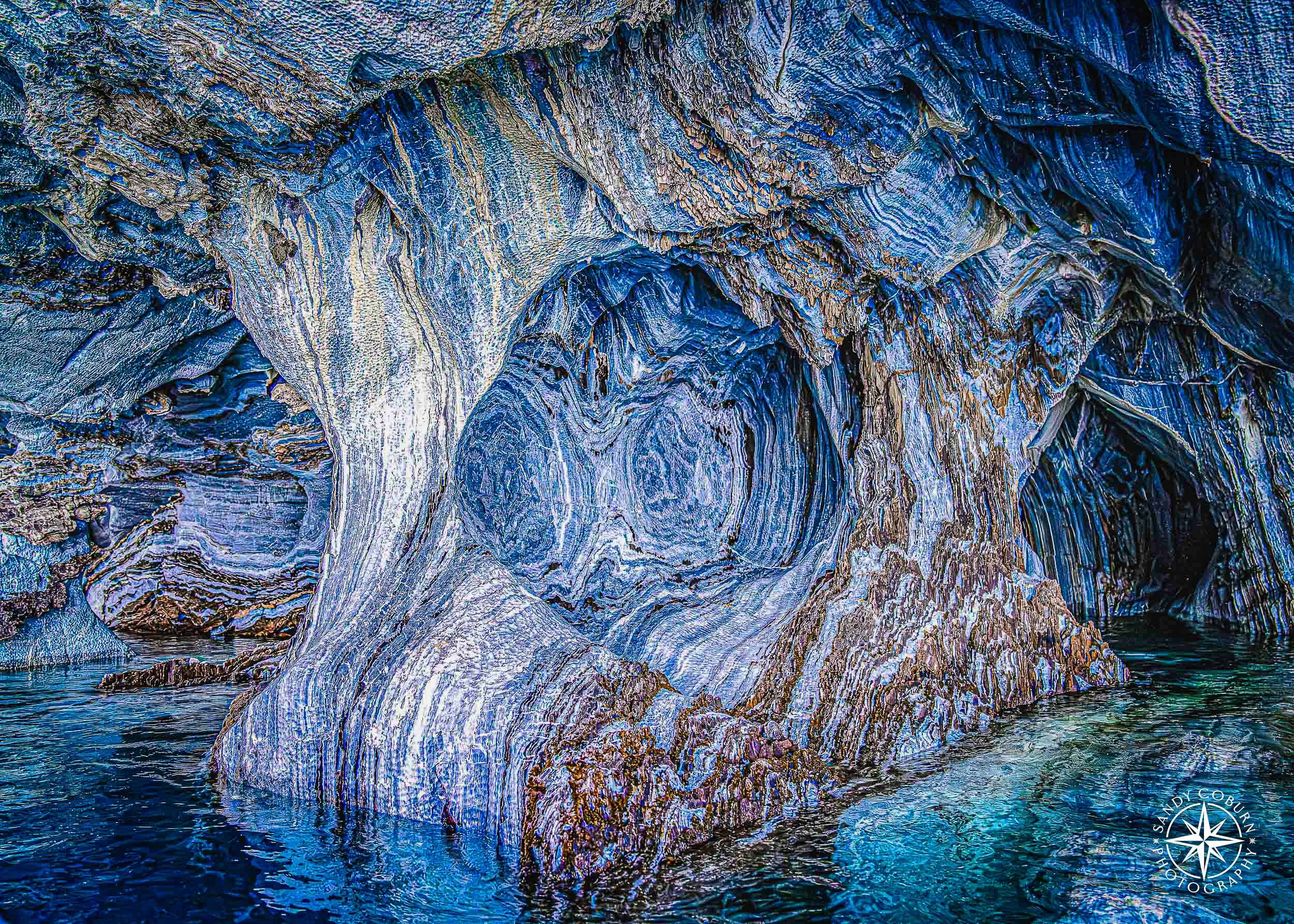 Blue-and-white marble spiral patterns framed by a cave arch above turquoise water.