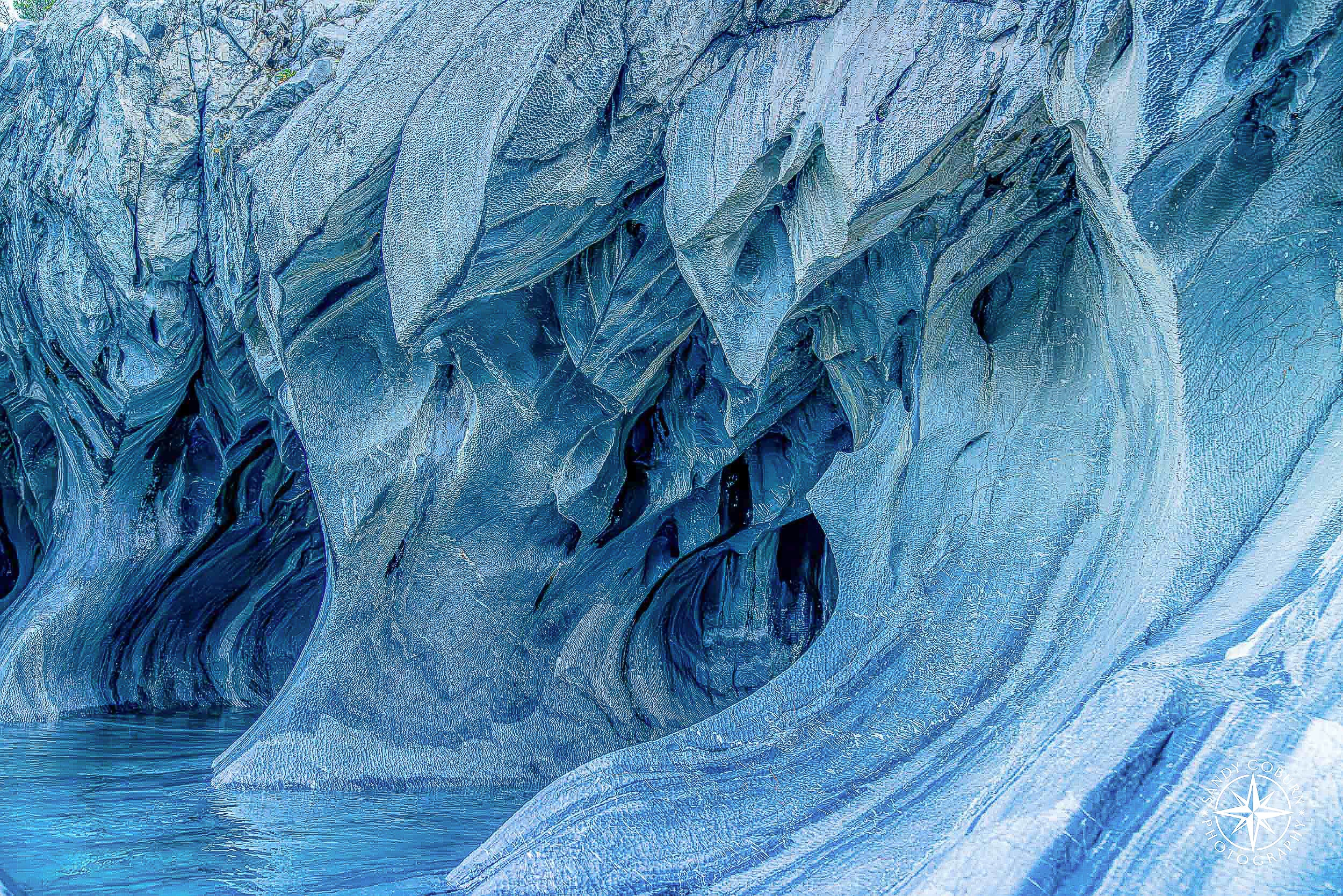 Interior view of marble cave with large teardrop-shaped opening and soft turquoise coloring.