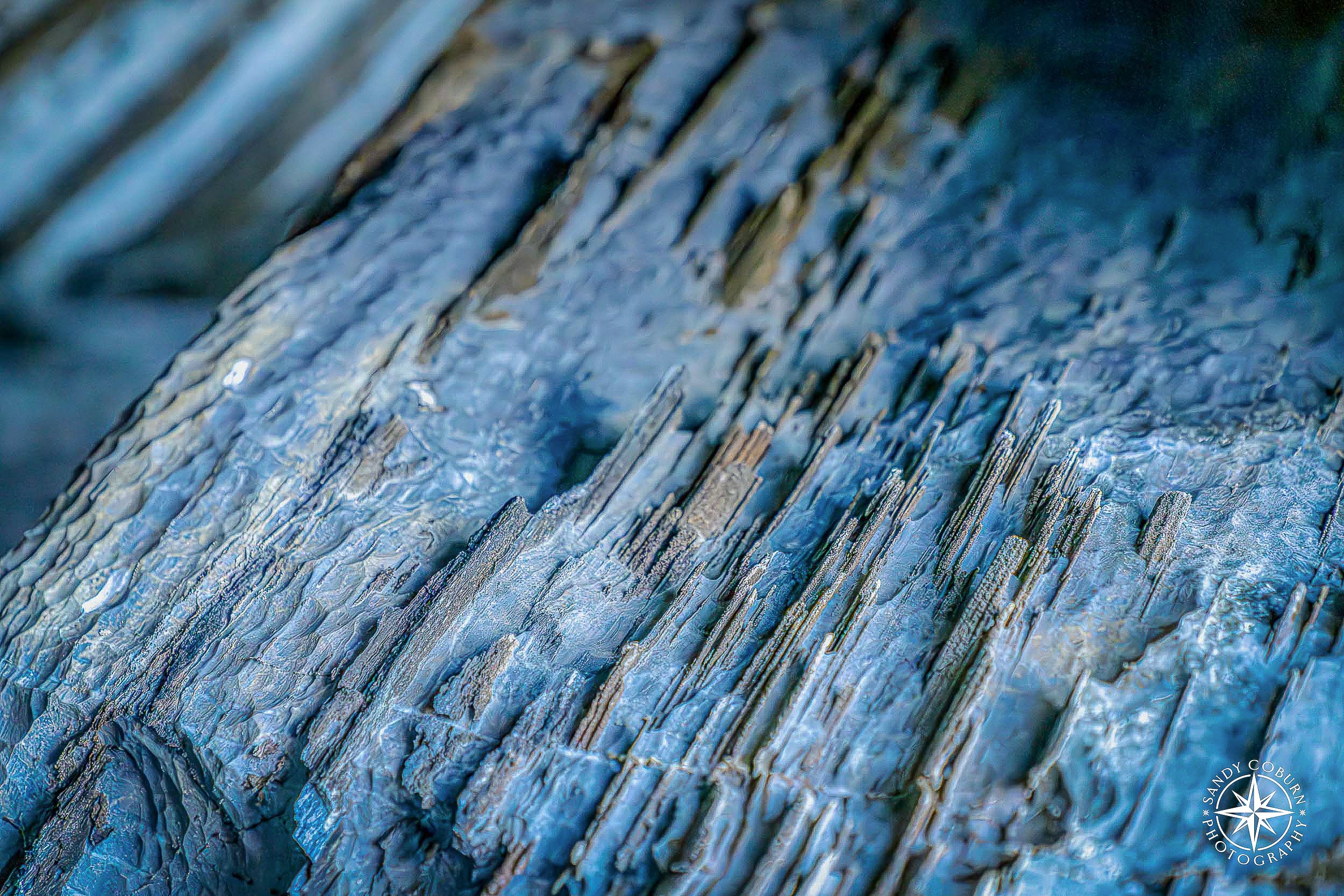 Close-up of fractured marble showing jagged, paper-thin mineral layers exposed by erosion.